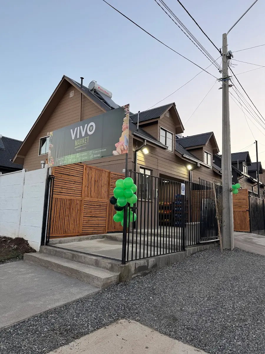 Fachada de día de Vivo Market con letrero verde y reja de madera