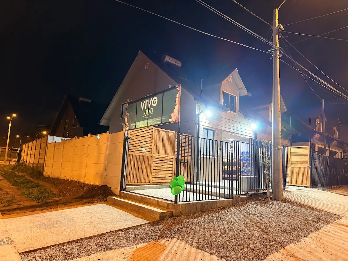 Fachada de Vivo Market de noche con el letrero iluminado