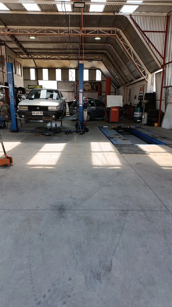 Interior del taller de Vulcanización Lontué con elevadores, un auto en servicio y estantes de neumáticos