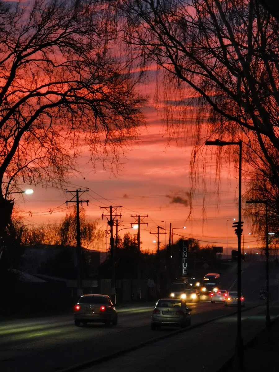 Atardecer en Lontué: la calle principal con el letrero vertical del pueblo y autos al volver del trabajo